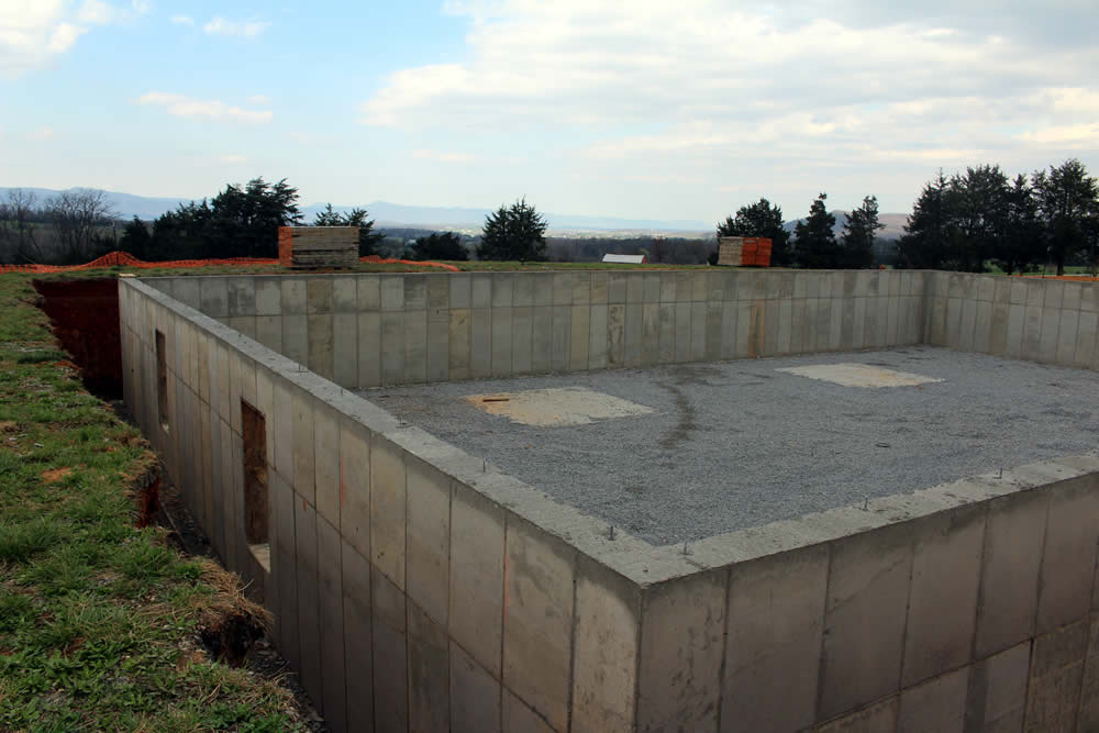 MARCH 25—The concrete having set sufficiently, the wall-forms are removed revealing the new foundation wall.