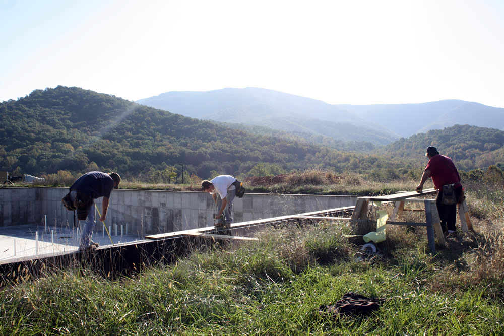 Workers attach a frame to the foundation, the first step in the first floor deck construction.